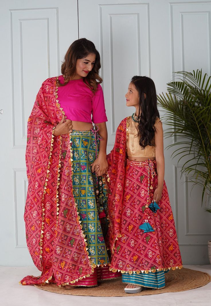 Lehenga set for Mother-Art Kota Silk Lehenga in Teal Blue.This attire with Cotton Lining is Enhanced with Dangles, Patola Print and Gota Lace Work Available with an Unstitched Art Silk Choli with Cotton Lining in Fuchsia and an Art Kota Silk Dupatta in Coral Pink. Choli Length- 12 to 15 inches.  Do note: Accessories shown in the image are for presentation purposes only and length may vary upto 2 inches.(Slight variation in actual color vs. image is possible). Lehenga set for Daughter:- Readymade Unstitched Floor-length Sets With Dupatta, Unstitched Bollywood Festive Sets, Unstitched Festive Bollywood Sets, Anarkali Sets For Festive Occasions, Festive Anarkali Sets For Festivals, Bollywood Style Art Silk Sets For Eid, Bollywood Art Silk Sets For Eid, Semi-stitched Bandhani Print Sets For Transitional Season, Floor-length Set With Zari Work For Eid