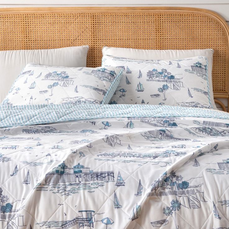 a bed with white and blue comforters in a bedroom next to a wicker headboard