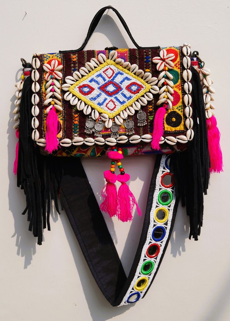 a colorful handbag hanging on the wall with tassels and beads around it