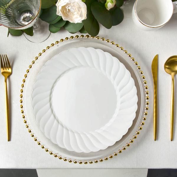 a white plate with gold beaded trim sits on a table next to silverware