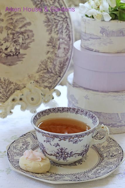 a tea cup and saucer sitting on a table next to three stacked cake plates