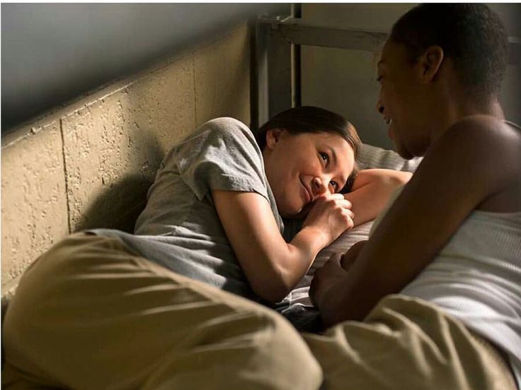 a man and woman laying in bed with each other looking at the same person's face