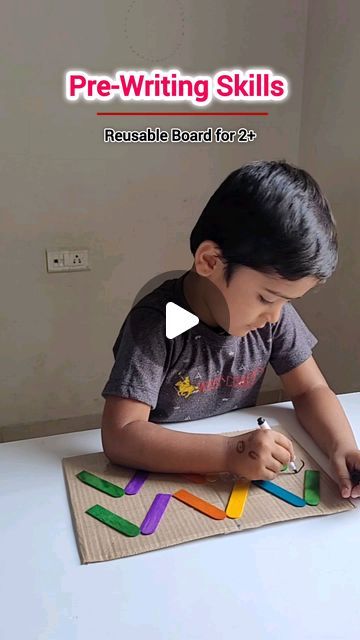 a young boy sitting at a table writing on a piece of paper with colored markers