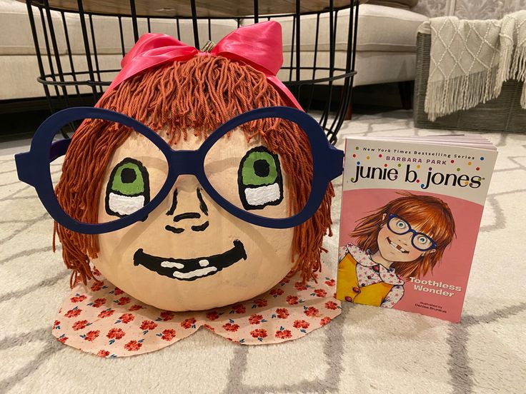 a stuffed doll with glasses and a book on the floor next to it's head