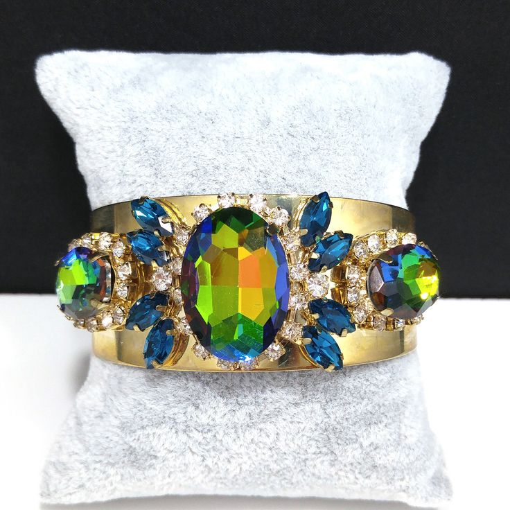 *Description: This is a gorgeous watermelon rhinestone crystal bracelet on a golden brass cuff which glitters and sparkles in the light. The vintage rhinestones are secured on a golden brass cuff and the reflective cuff adds additional sparkle to the bracelet. There is one large watermelon rhinestone in the center, surrounded by clear rhinestones and sapphire blue marquise cut rhinestones. On each side of the center stone are two more watermelon rhinestones, a little smaller in size, one on each Formal Earrings, Brass Cuff Bracelet, Vintage Christmas Gifts, Book Pieces, Brass Cuff, Sapphire Blue, Blue Rhinestones, Crystal Bracelet, Marquise Cut