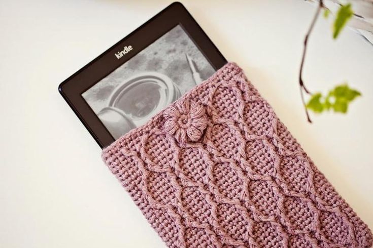 a pink knitted tablet case sitting on top of a white table next to a plant