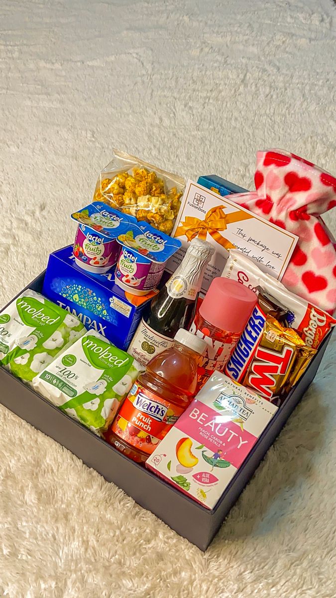 a box filled with snacks and drinks on top of a white carpeted floor in front of a window