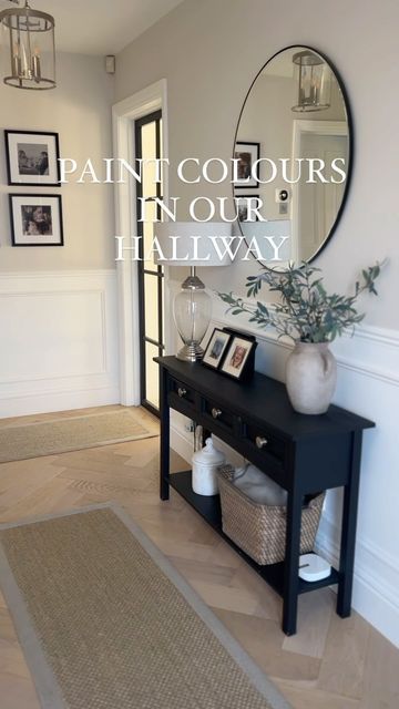 a hallway with a black table, mirror and pictures on the wall in front of it