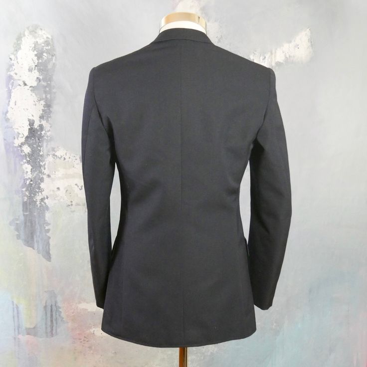 This 1960s German vintage double-breasted naval officer's jacket has peak lapels and padded shoulders, and closes in the front with two gold anchor buttons (six in total show on the front). The handsome blazer has three pockets on the front, and the left chest pocket has small pinholes where a patch was removed. The jacket is lined in a navy blue satin viscose fabric, and has three inner pockets. Brand label: Kleiverfabrik Knab (Germany) Size: 36 US/UK Material: 55% polyester, 45% wool Condition Fitted Double-breasted Peacoat With Hidden Buttons, Navy Fitted Blazer For Tailoring, Fitted Double-breasted Peacoat For Business, Fitted Navy Blazer For Tailoring, Fitted Double-breasted Sport Coat With Buttons, Fitted Double-breasted Peacoat With Notch Lapel, Fitted Double-breasted Blazer With Gold Buttons, Fitted Double-breasted Peacoat For Tailoring, Fitted Peacoat With Notch Lapel And Double-breasted Button