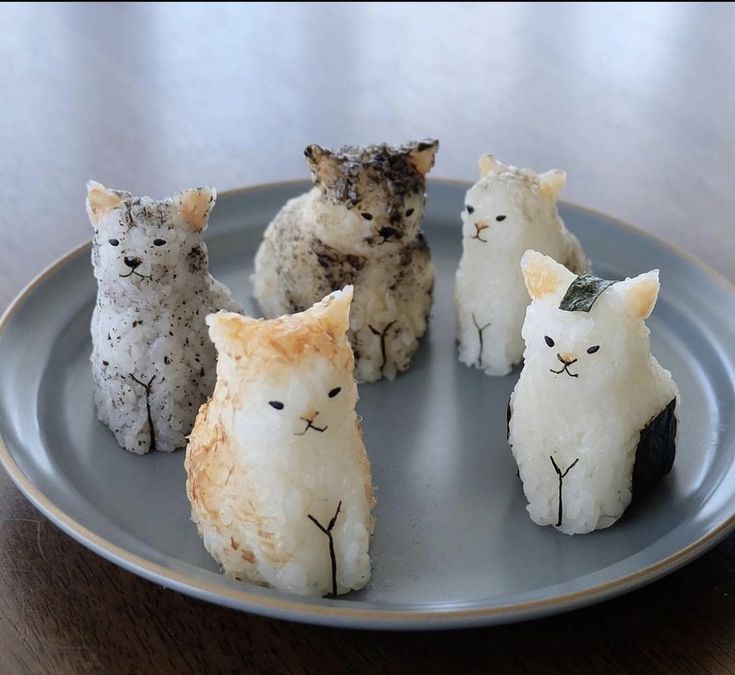 four cats made out of rice krispy treats sitting on a plate with one cat looking at the camera