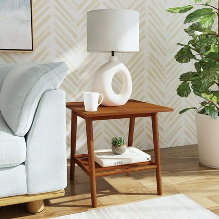 a living room with a couch, table and potted plant on the floor next to it