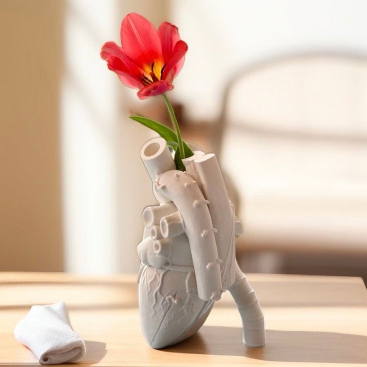 a heart shaped vase with a flower in it