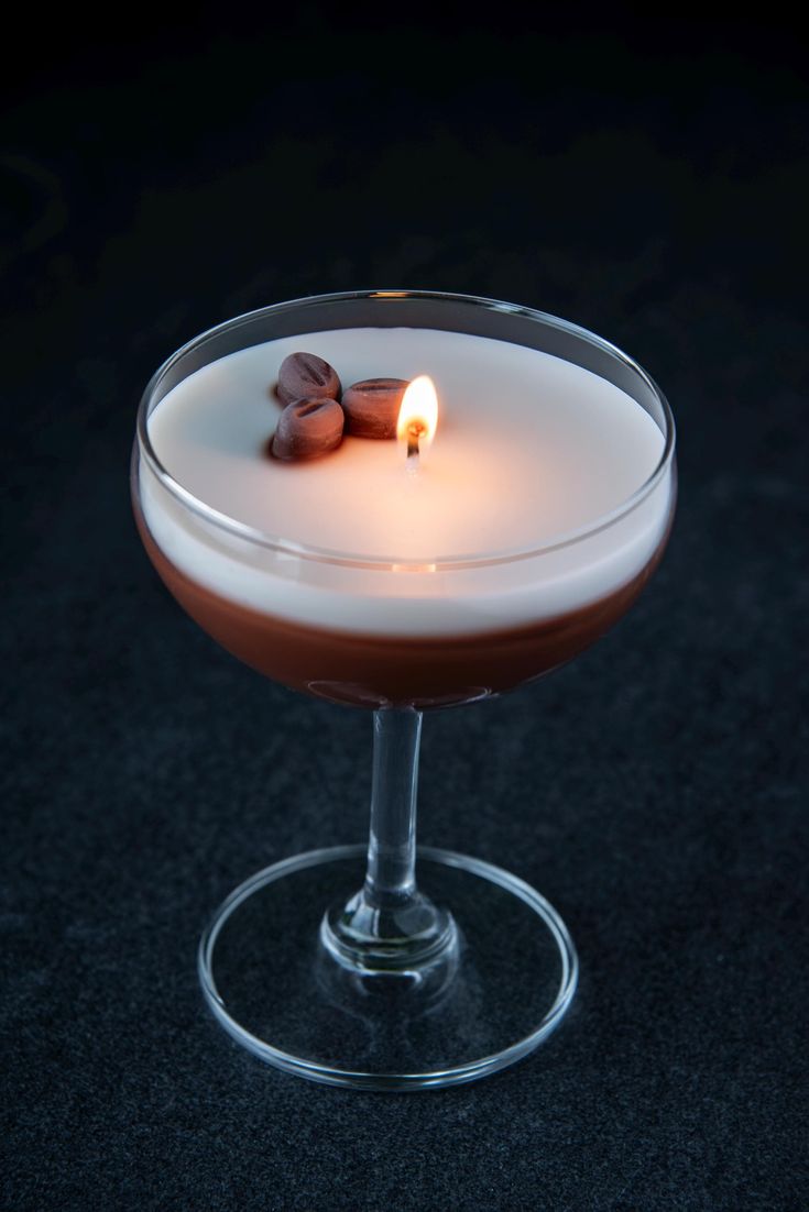 a drink with a candle in it sitting on a table