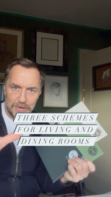 a man sitting at a desk holding up some type of paper that says three schemes for living and dining rooms