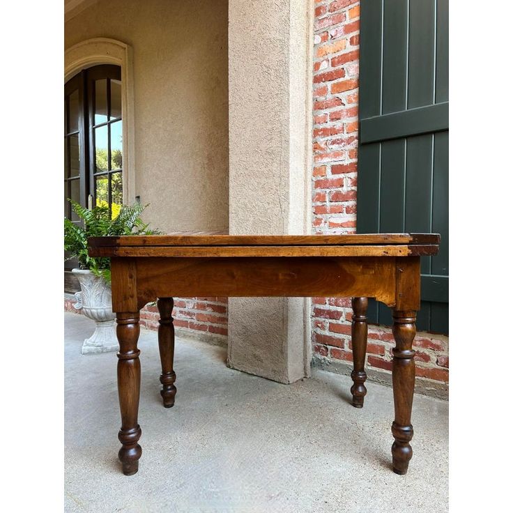 a wooden table sitting in front of a brick building