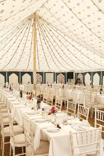 a large tent with tables and chairs set up for a formal function in white linens