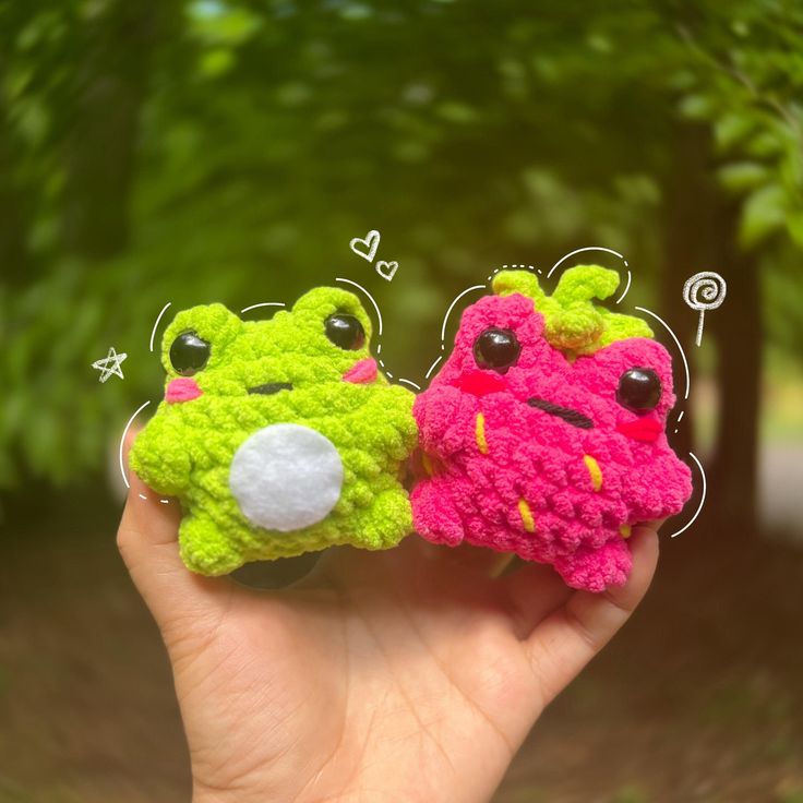 two small crocheted toys are held in the palm of someone's hand