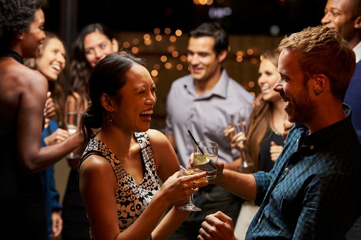 a group of people standing around each other holding wine glasses and smiling at one another