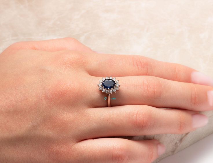 a woman's hand with a ring on it and a blue stone in the middle