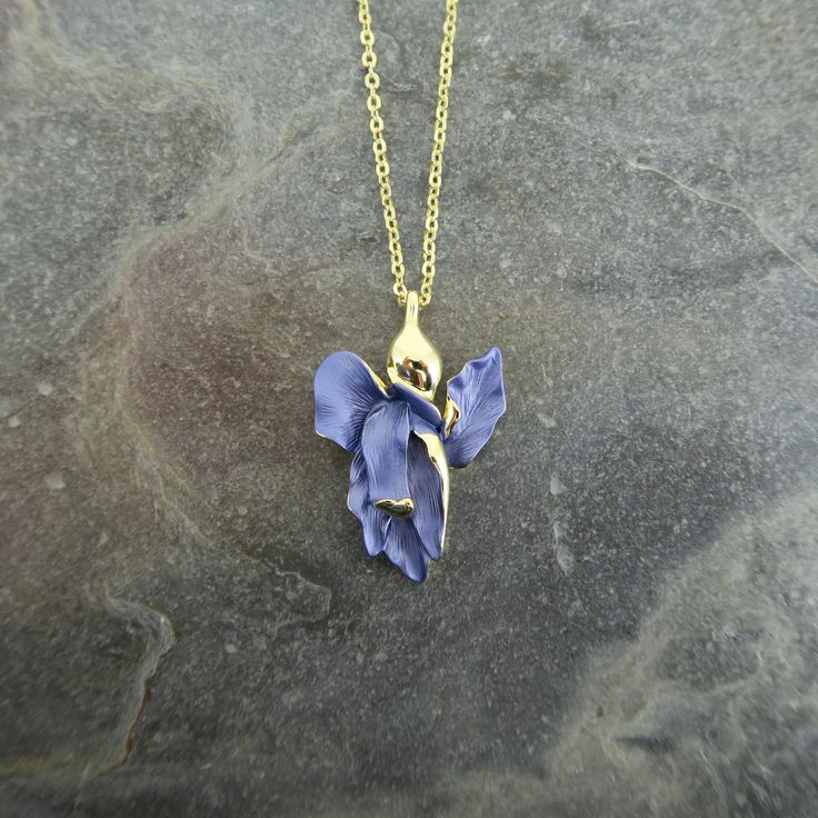 Our Iris flower necklace adds elegance to any outfit and make a fabulous Valentines gift for a flower lover. Each necklace is hand finished in blue enamel. This beautiful necklace embodies nature with its intricate realistic design and attention to detail. Designed by us, in our London office. The Iris is a symbol of hope, wisdom, trust and valor. Irises make fabulous gifts for nature lovers, they are the birth flower for the month of February, the gift to give for a 25th wedding anniversary and perfect for any occasion.  Size: (W) 21mm x (L) 32mm x (drop) 48.5cm Metal colour: gold Necklace clasp: lobster Chain length: 41cm chain with 7.5cm extension chain Each item is presented on a recycled paper gift card (as shown), packed in a biodegradable bag and then placed in an eco-friendly envel Violet Flower Necklace, Birth Flower Jewelry, Iris Necklace, February Birth Flower, February Birth Flowers, Flower Necklace Gold, Necklace Clasp, London Office, Iris Flower