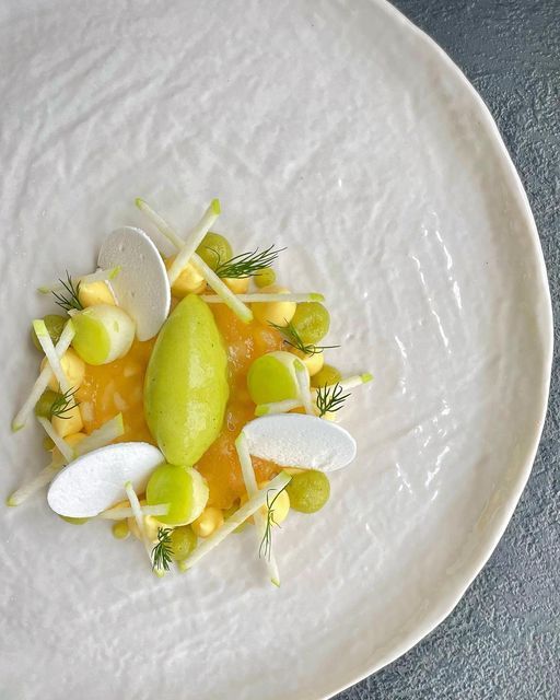 a white plate topped with fruit and vegetables on top of a blue tableclothed surface