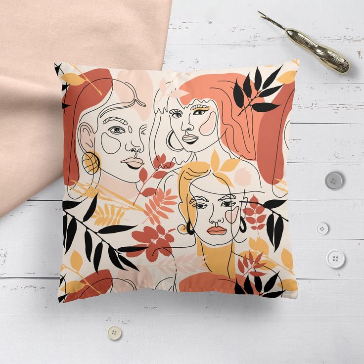 an orange and yellow pillow with three women on it next to a pair of scissors