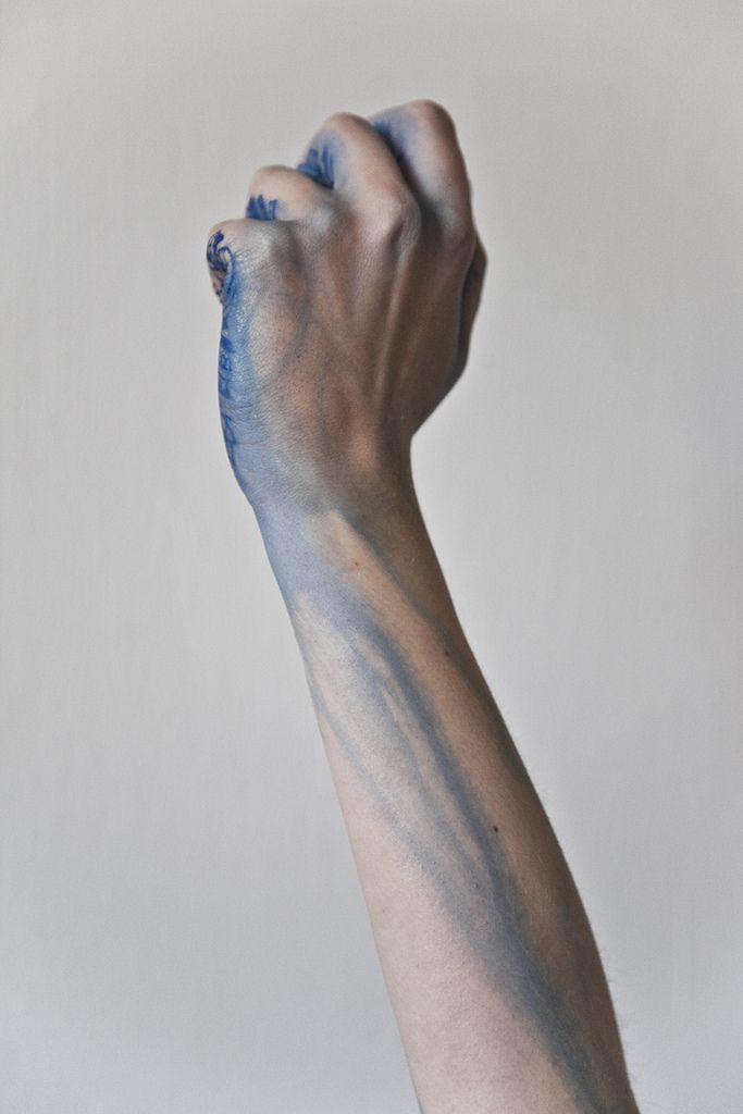 a person's arm with blue paint on it and one hand in the air