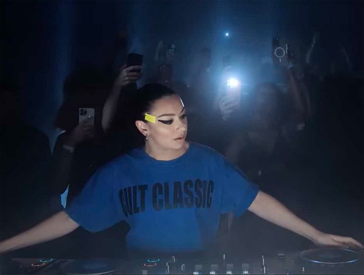 a woman in a blue shirt djing at a party