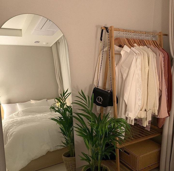 a bedroom with a bed, mirror and plant in the corner next to an ironing board