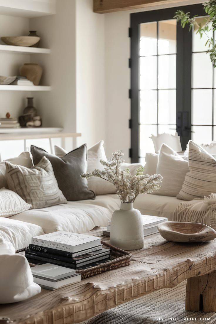 a living room filled with white furniture and lots of pillows on top of a wooden table