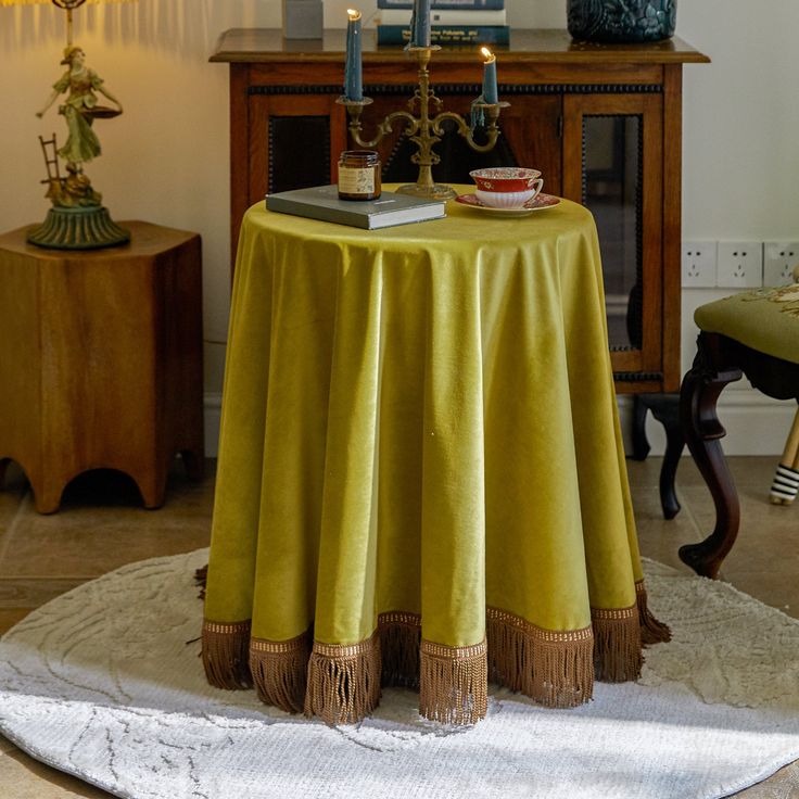 a table with two candles on it in a room next to a chair and other furniture