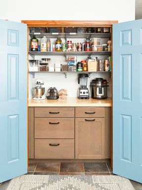 a kitchen with blue doors opened to reveal the pantry and coffee maker on the counter