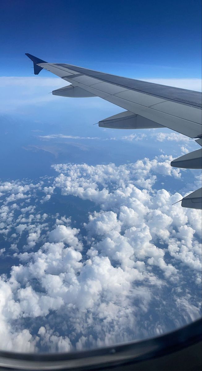 the view from an airplane window shows clouds and blue sky with white puffy clouds