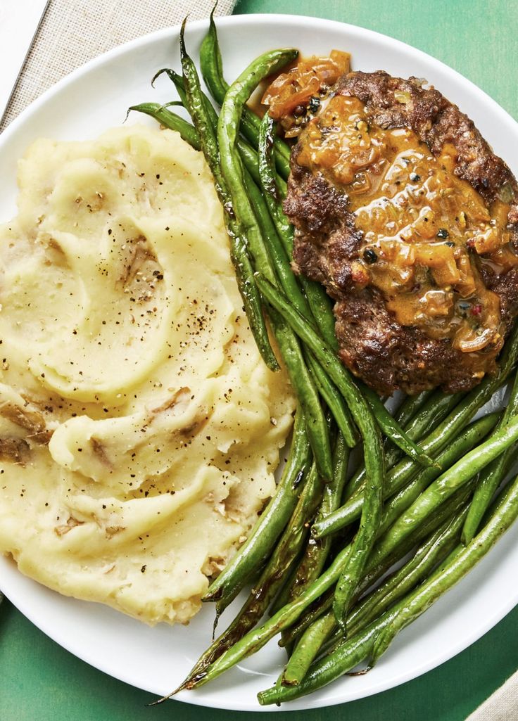 a white plate topped with green beans and mashed potatoes next to meatloaf