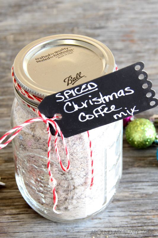 a glass jar filled with christmas coffee mix on top of a wooden table next to ornaments