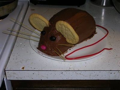 a cake shaped like a mouse sitting on top of a white plate with sticks sticking out of it