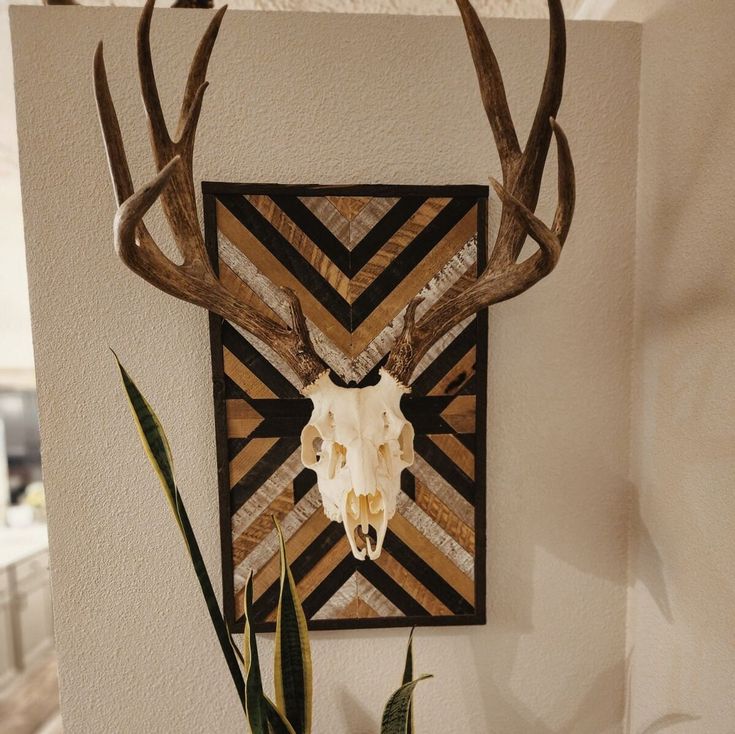 a deer skull mounted to the side of a wall next to a potted plant