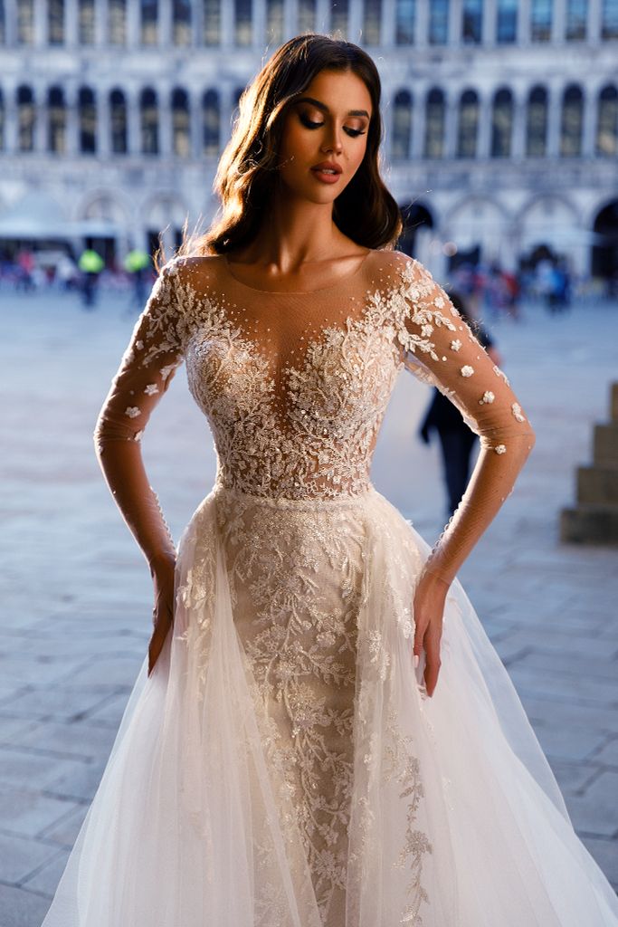 a woman in a wedding dress posing for the camera with her hands on her hips