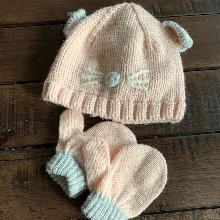 two knitted hats and mittens laying on top of a wooden floor