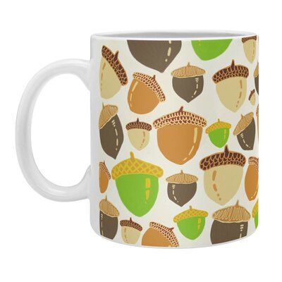 a white coffee mug with acorns and leaves on the inside, sitting in front of a white background