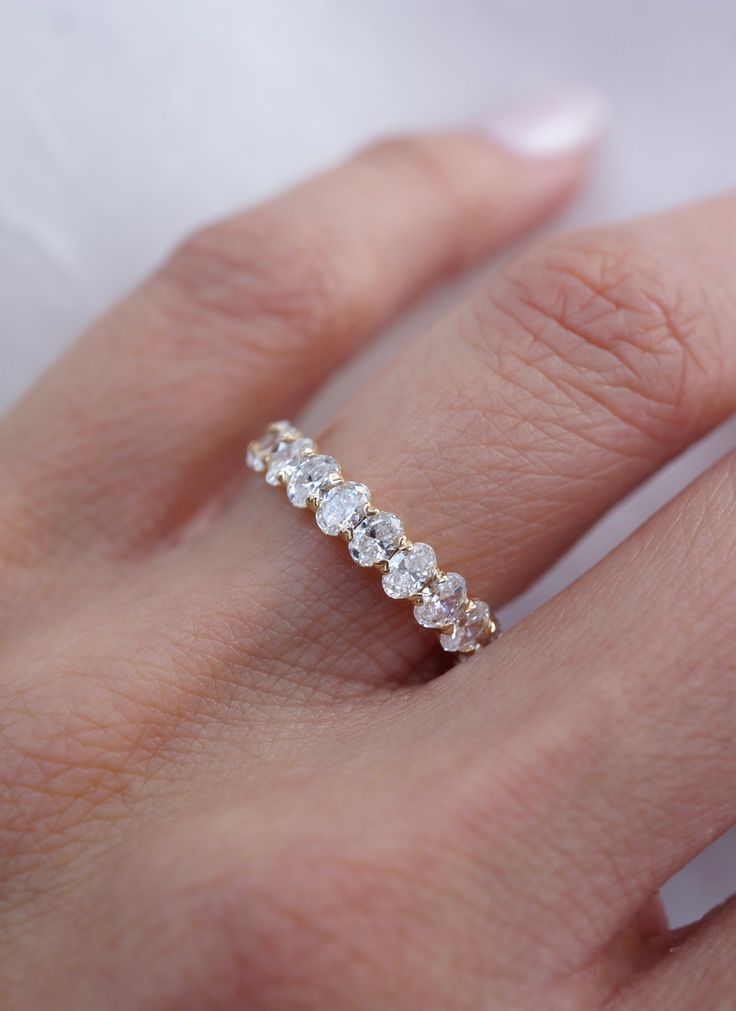 a woman's hand with a diamond ring on top of her finger and the band is