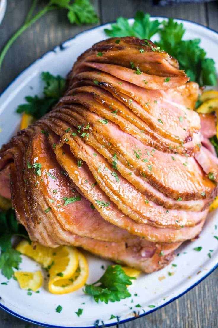 the ham is sliced up and ready to be served on the plate with lemon wedges