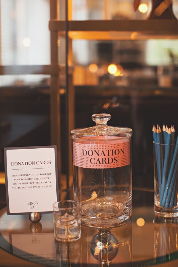 there is a glass jar on the table next to two glasses and a sign that says donation cards