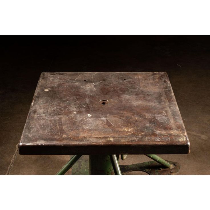 an old wooden table sitting on top of a green metal stool in a dark room