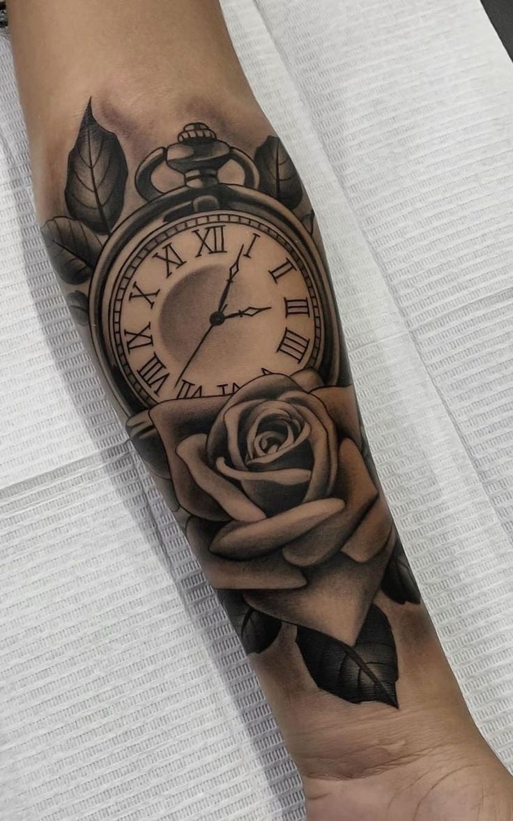 a black and white rose tattoo on the arm with an old style clock in the middle