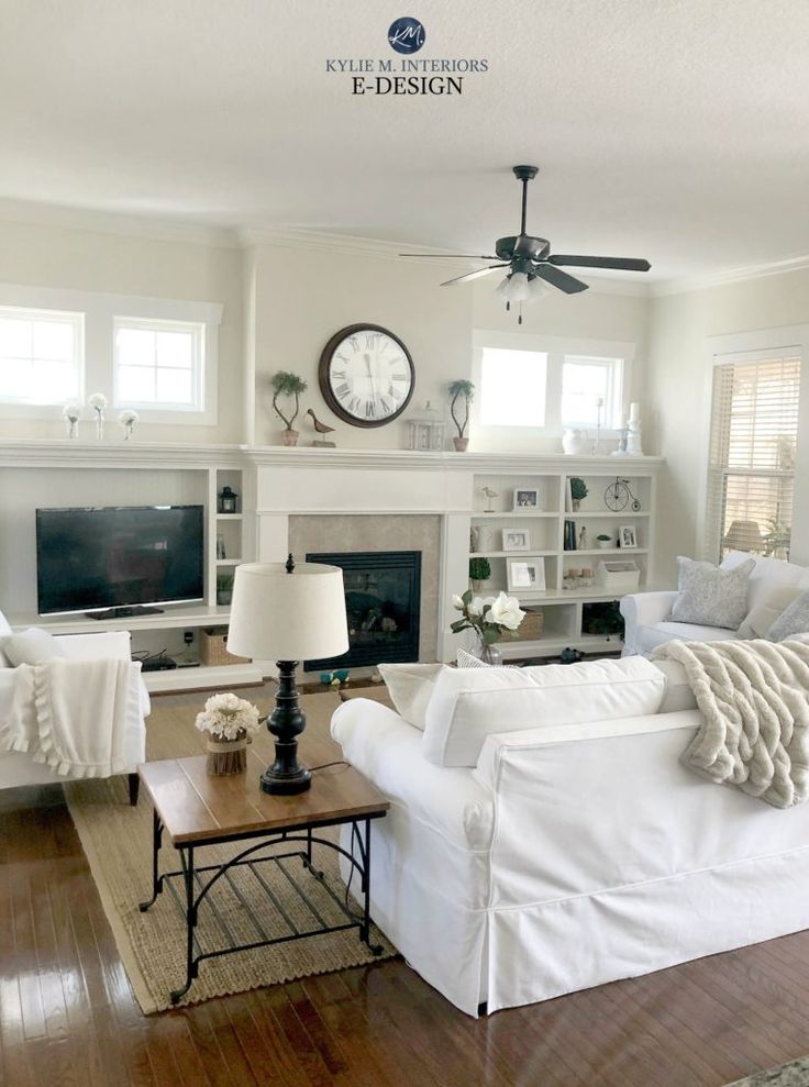 a living room filled with furniture and a clock on the wall above it's fireplace