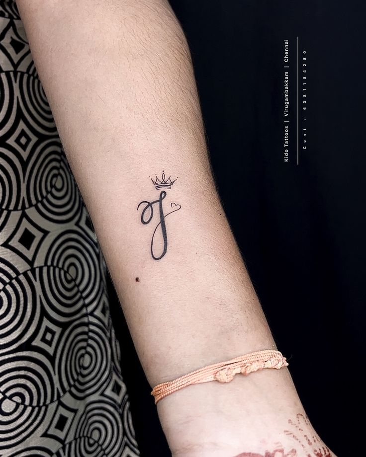 a woman's arm with a tattoo on it that reads f and has a crown