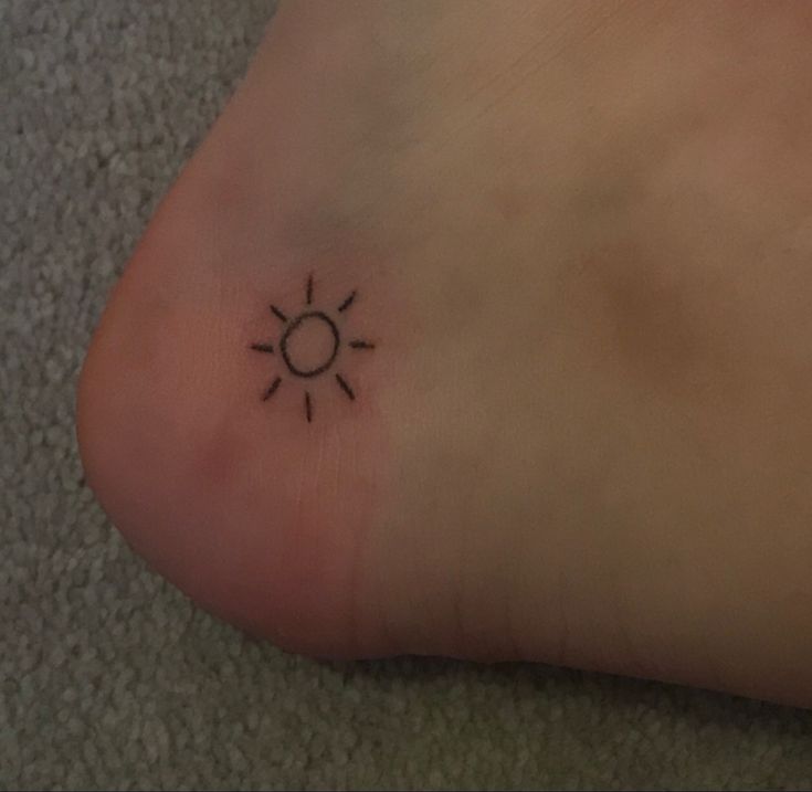 a small tattoo on the foot of a person with a sun in the middle of it