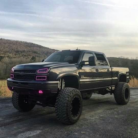 a large black truck parked on top of a dirt road