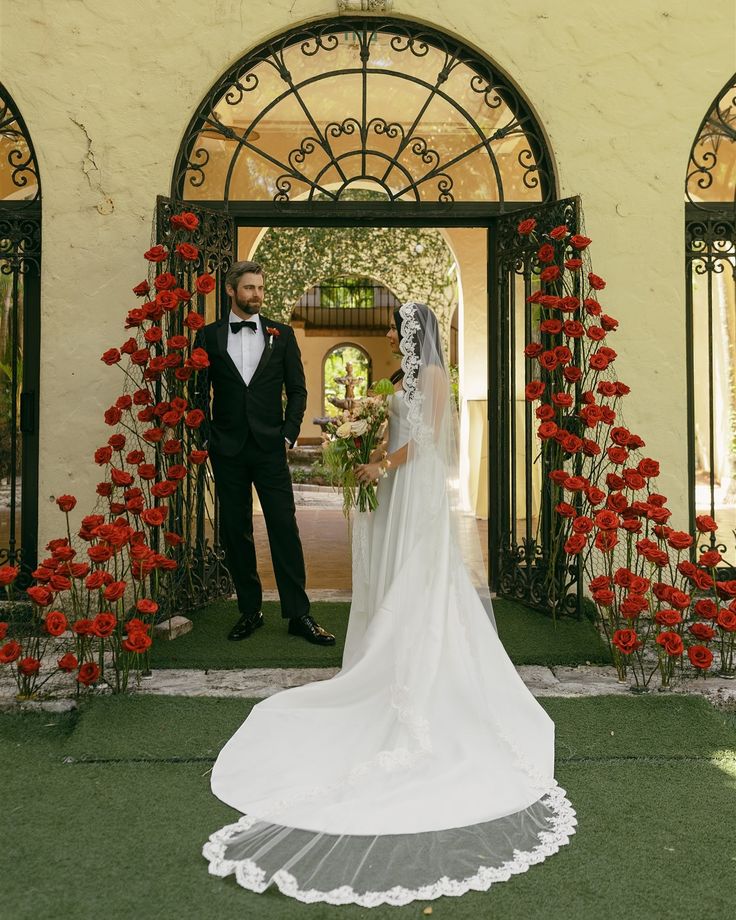 a bride and groom standing in front of an archway